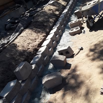 A segmental-block retaining wall under construction with staged blocks.