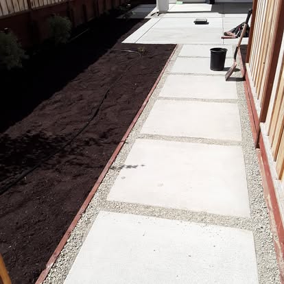 A paver walkway set in gravel joints alongside a fresh mulch bed.