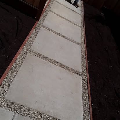 A paver walkway with brick edging leading through the yard.